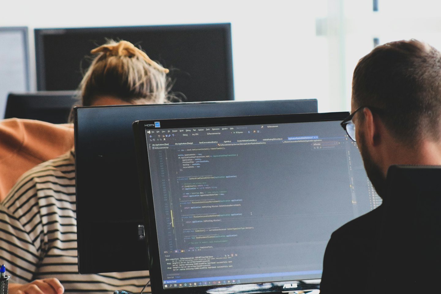 Two professionals working at computer workstations in a modern office.